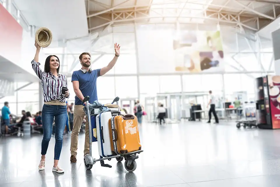 Pasažéři po příletu s kufry na letišti